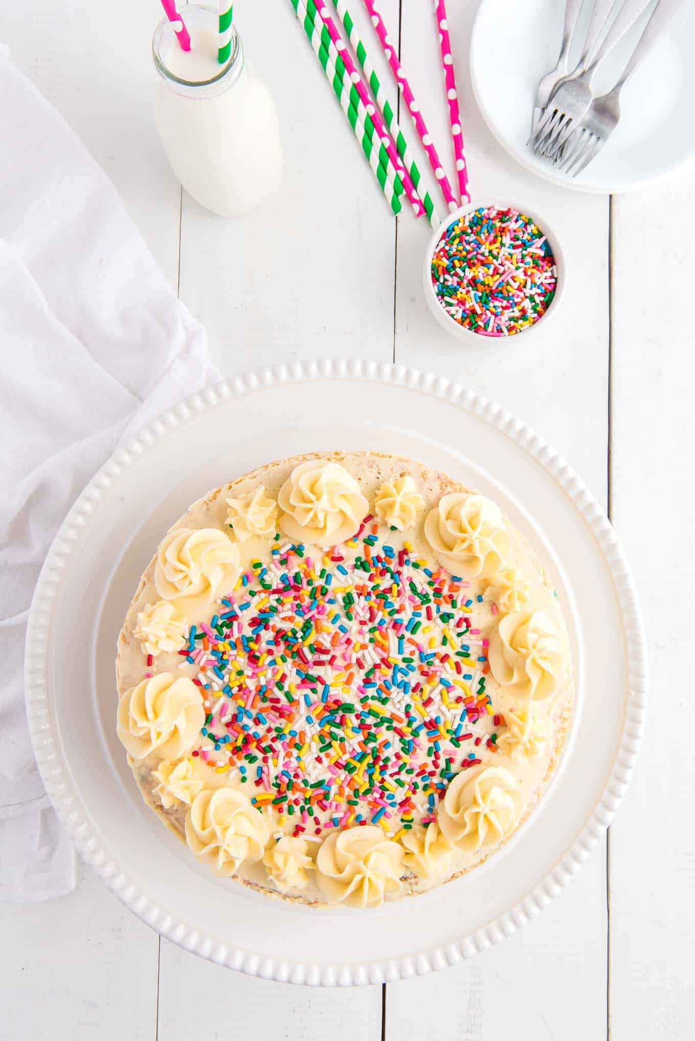 Funfetti cake on a white platter topped with sprinkles.
