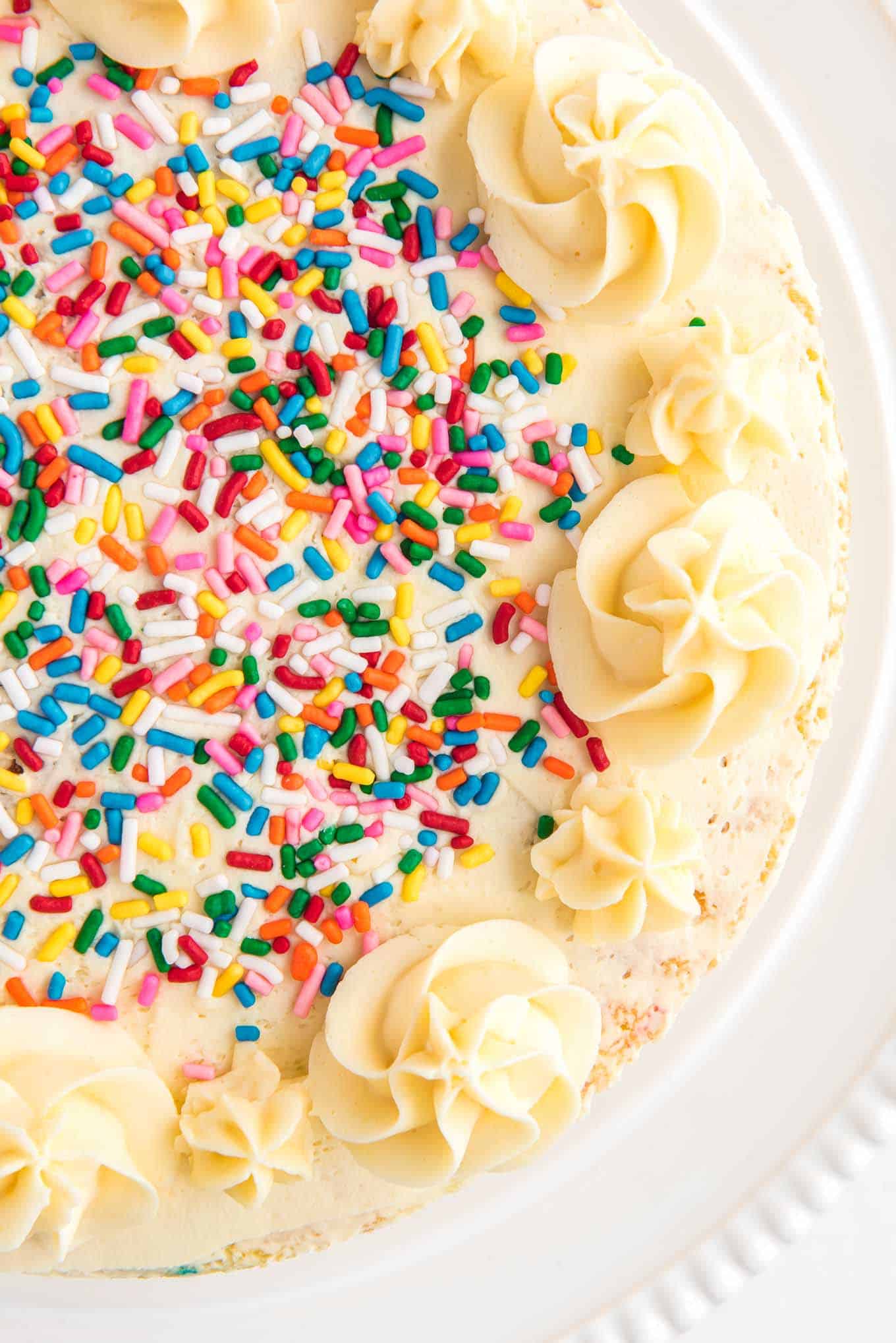 Overhead of a cake on the table topped with creamy frosting and spirnkles.