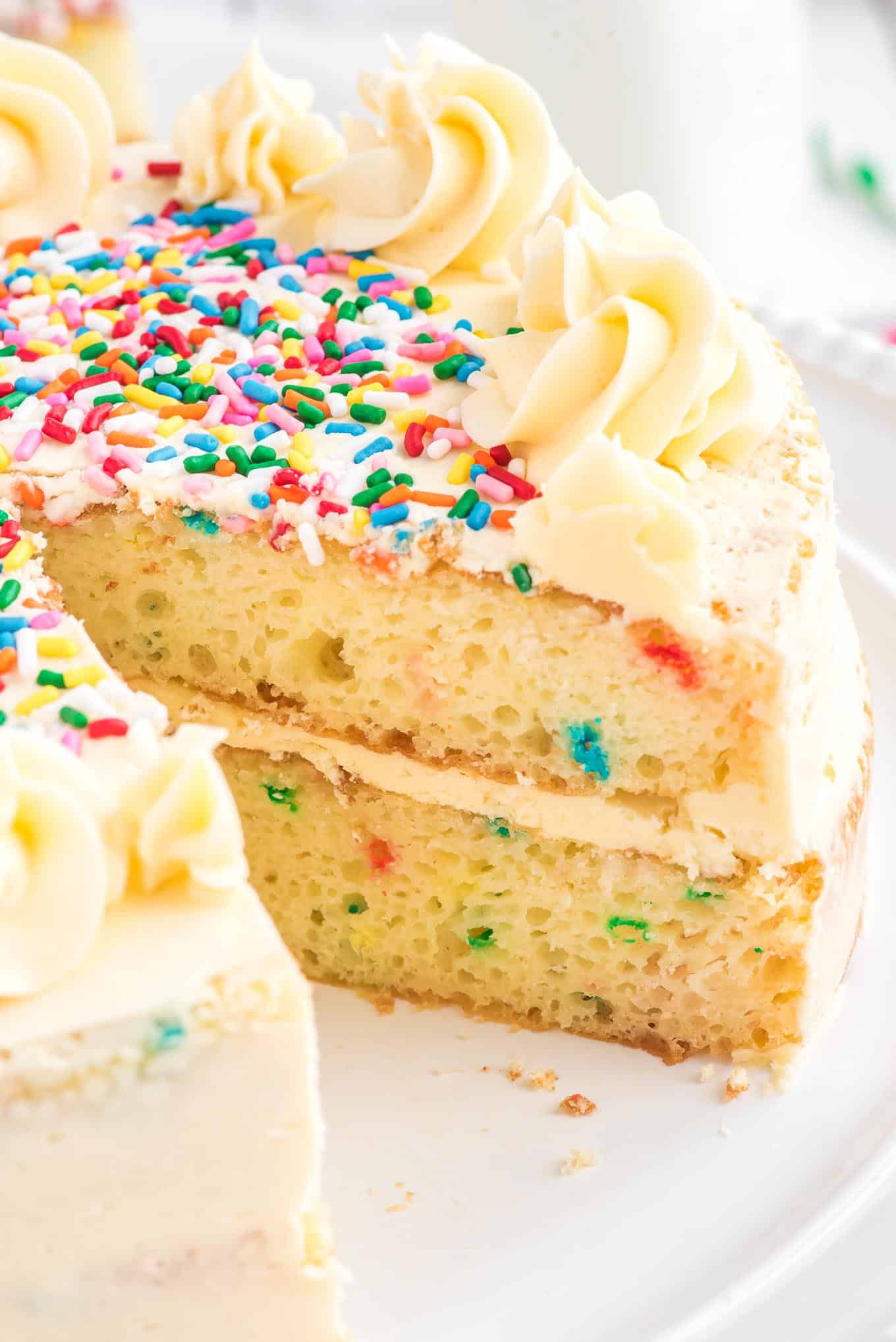 Funfetti cake on a platter with a slice missing to show the inside of the cake.