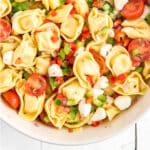 A bowl of Greek tortellini salad with half of the bowl showing.