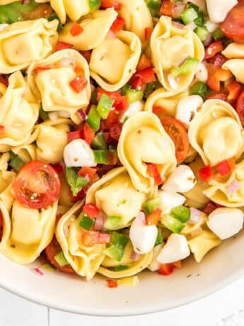 A bowl of Greek tortellini salad with half of the bowl showing.