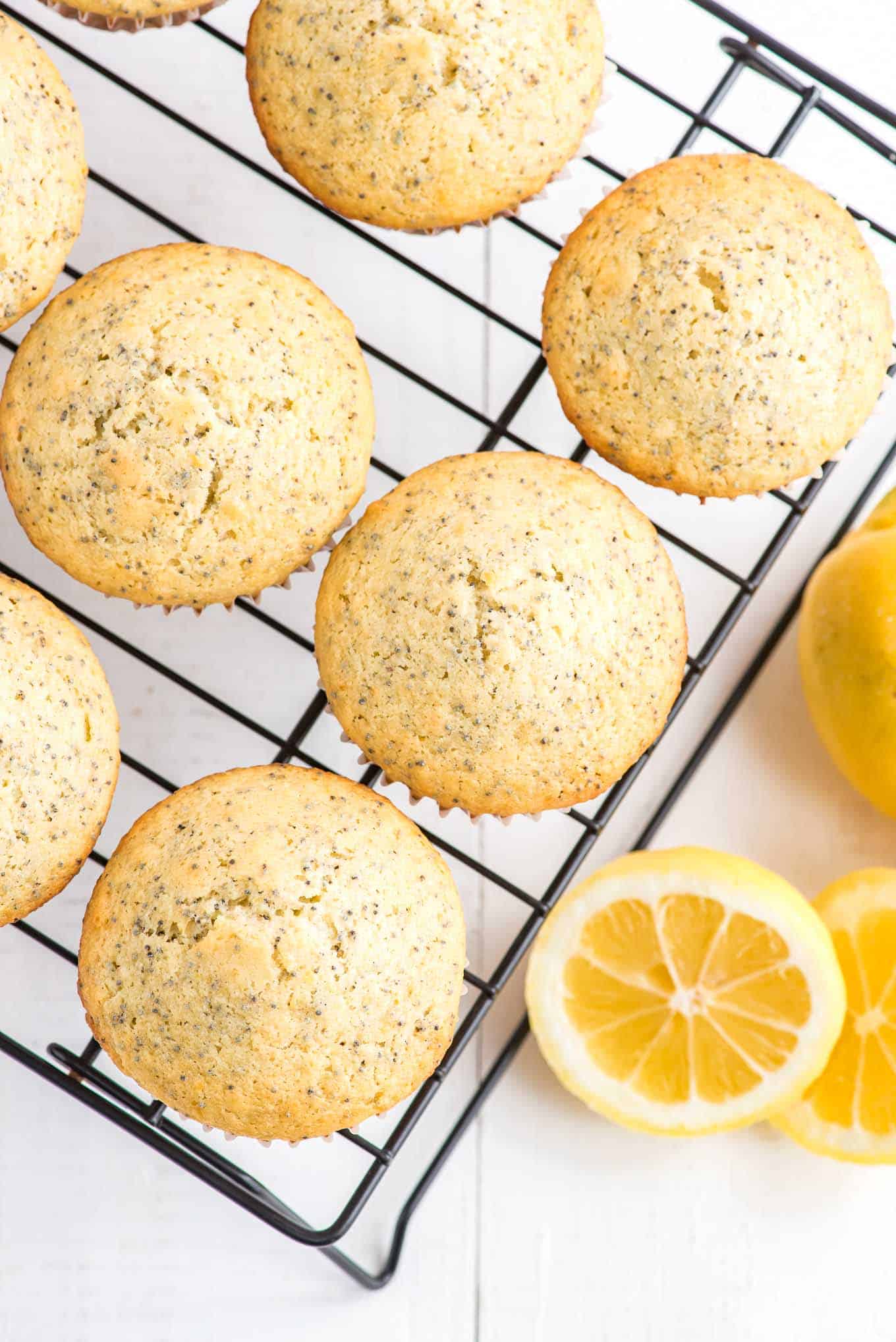 Overhead of muffins on a cooling rack with a lemon and lemon slices next to it.