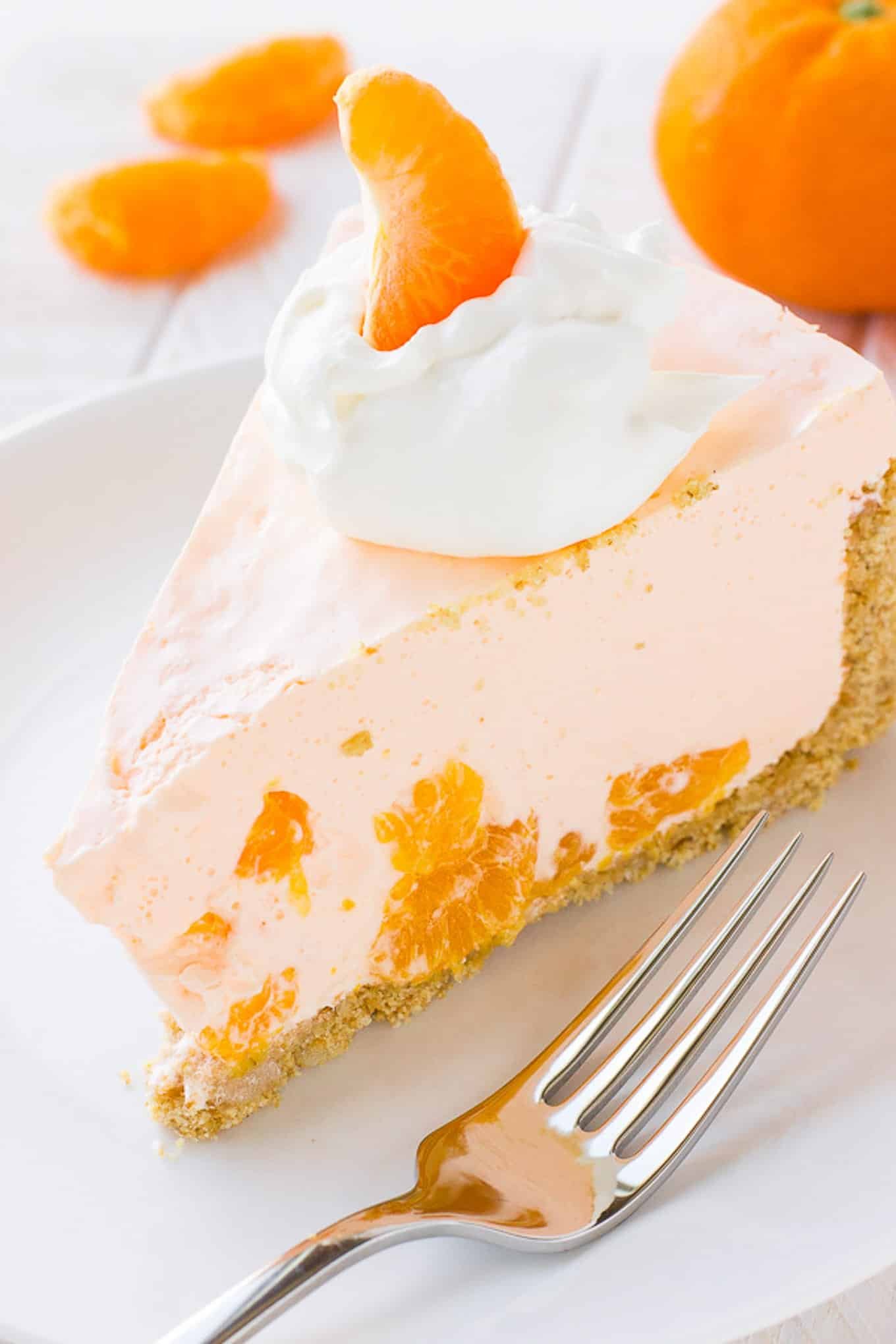 A slice of orange cream pie on a plate with a fork. 