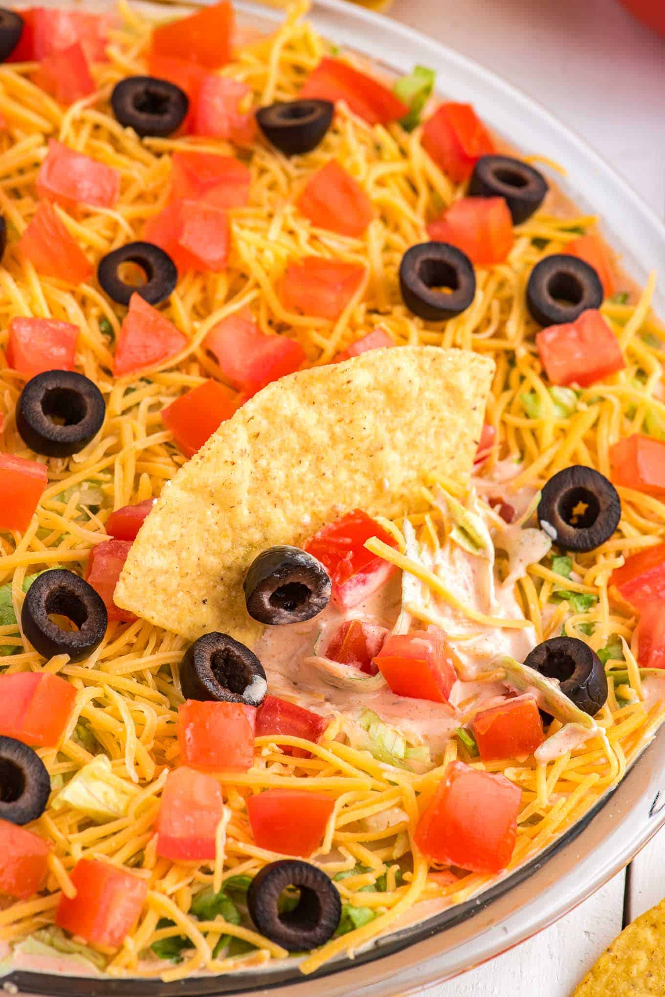Taco dip in a bowl with a chip laying on top with some dip on it.