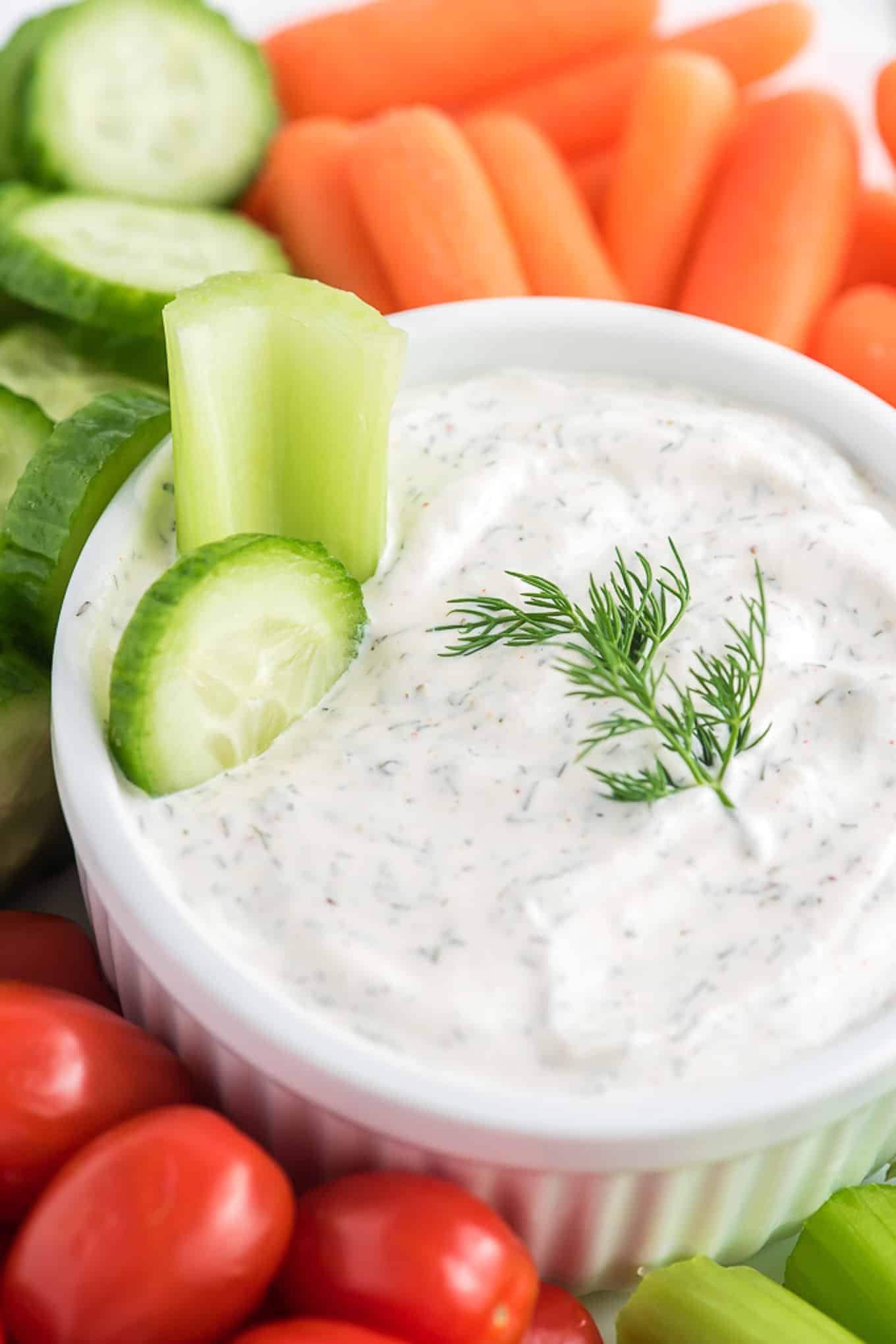A cucumber and celery stick in dill dip with sour cream.