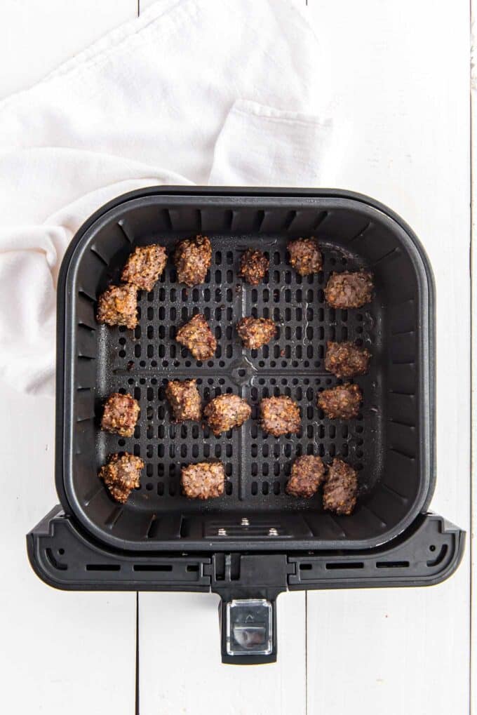 Cooked steak bites in the air fryer basket.