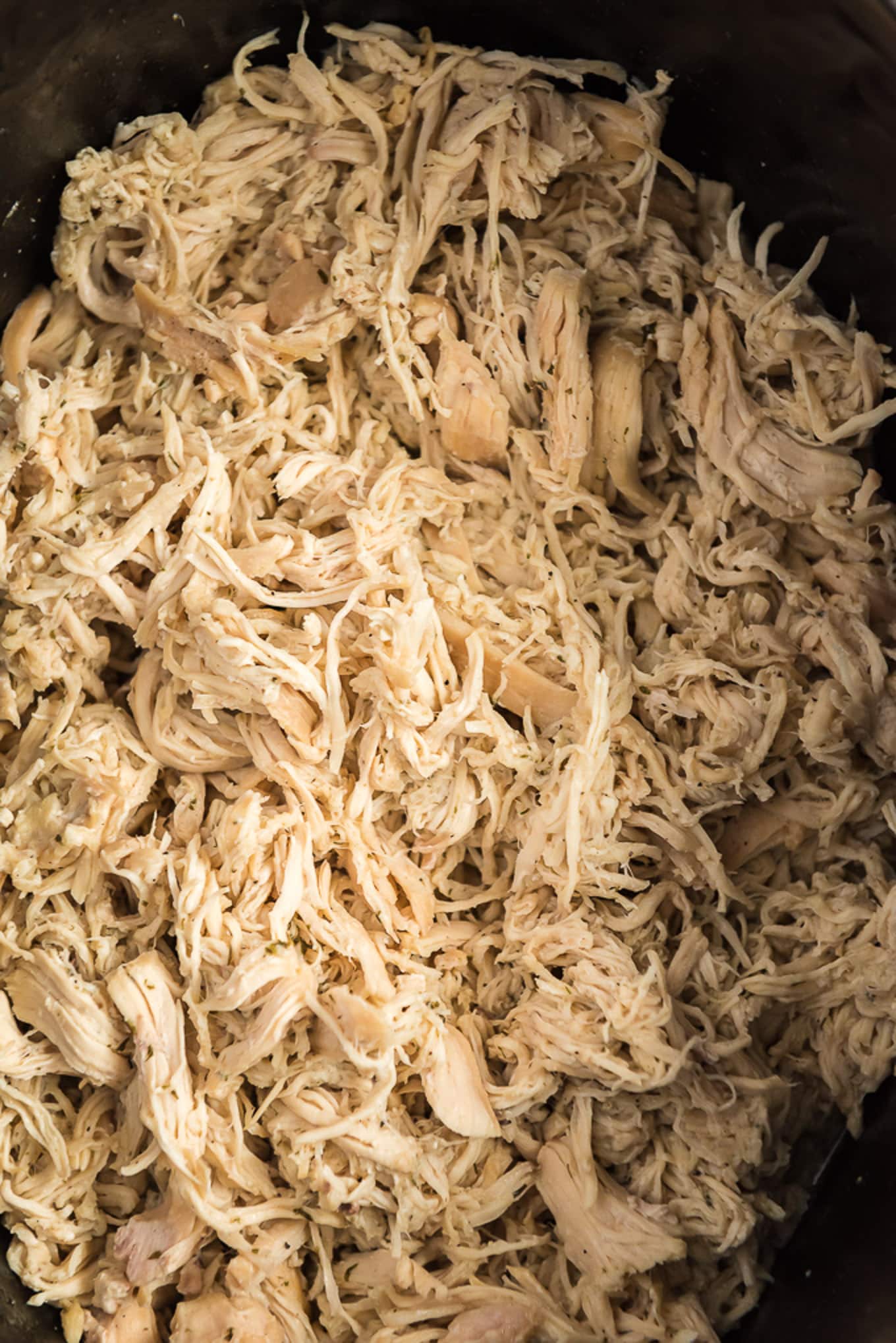 Shredded chicken in a crockpot ready to use in recipes.