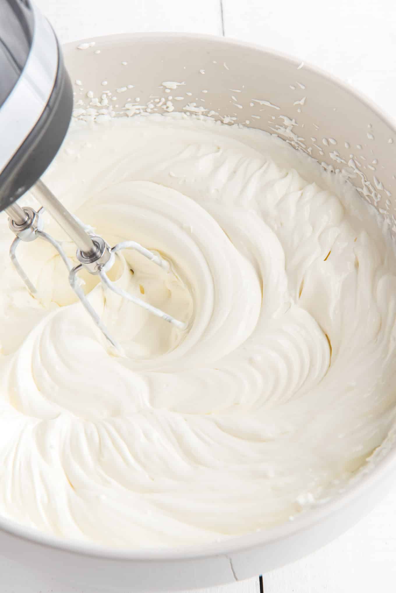 Mixing the cream cheese and sour cream together with an electric mixer.