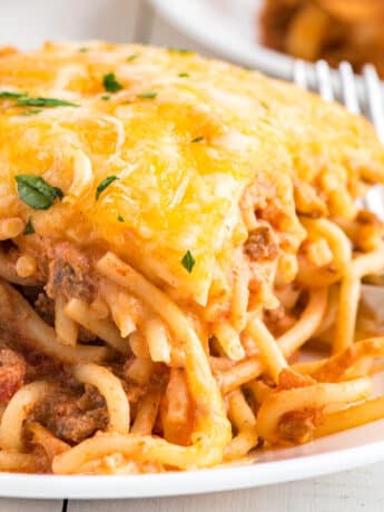 A portion of spaghetti casserole on a plate with a fork to the side.