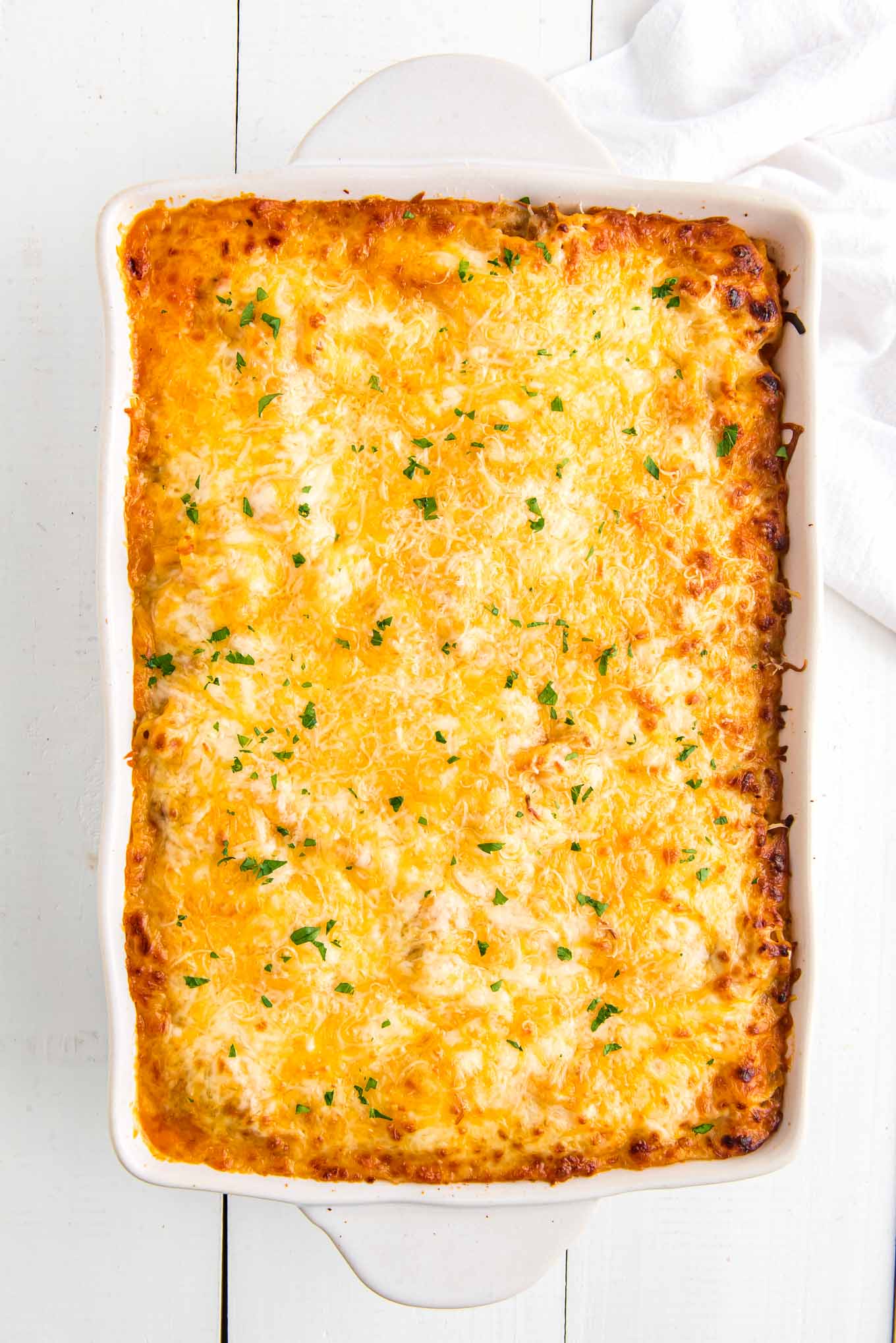 An overhead of spaghetti bake casserole lightly sprinkled with chopped parsley.