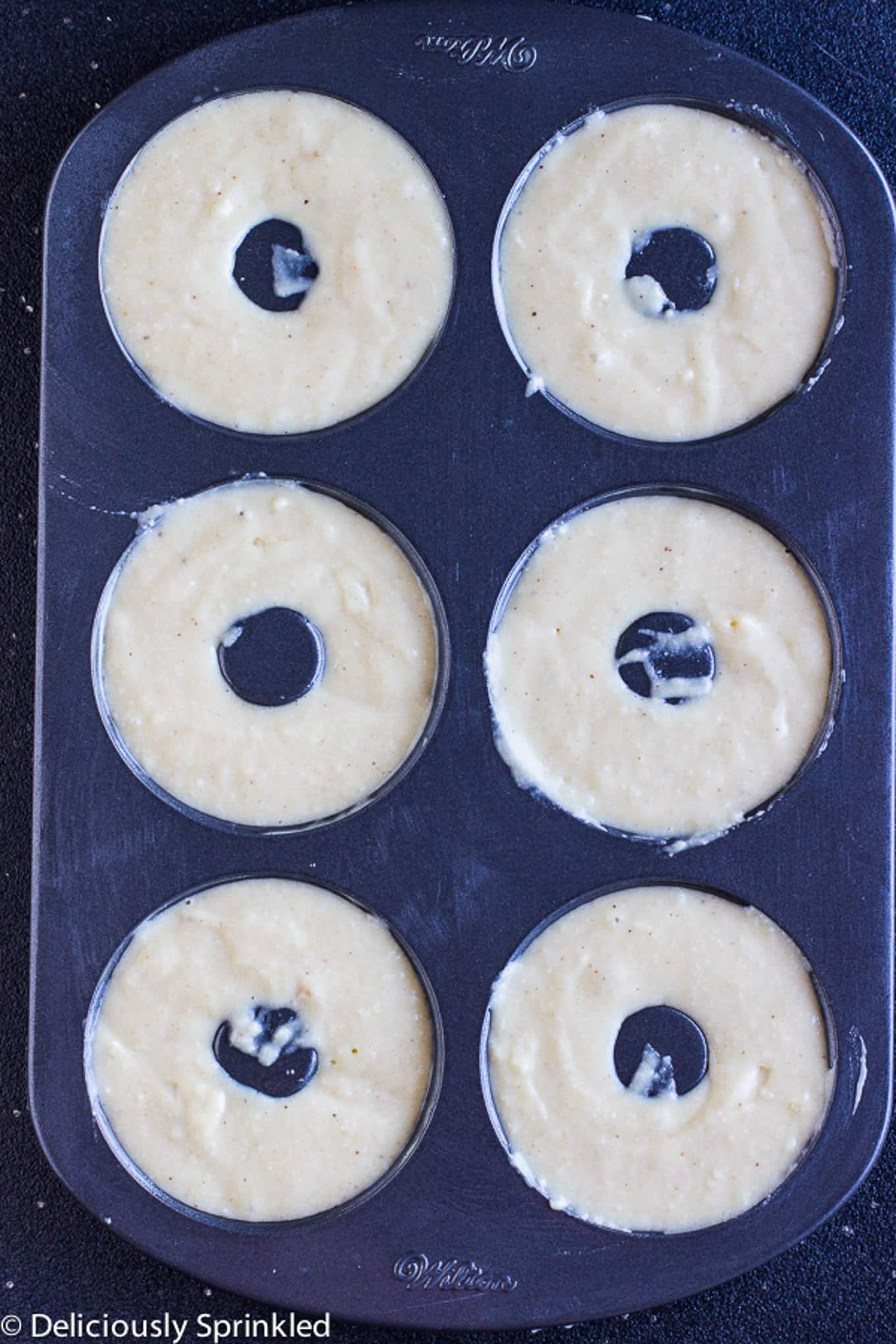 Vanilla donut batter in a donut pan before baking.