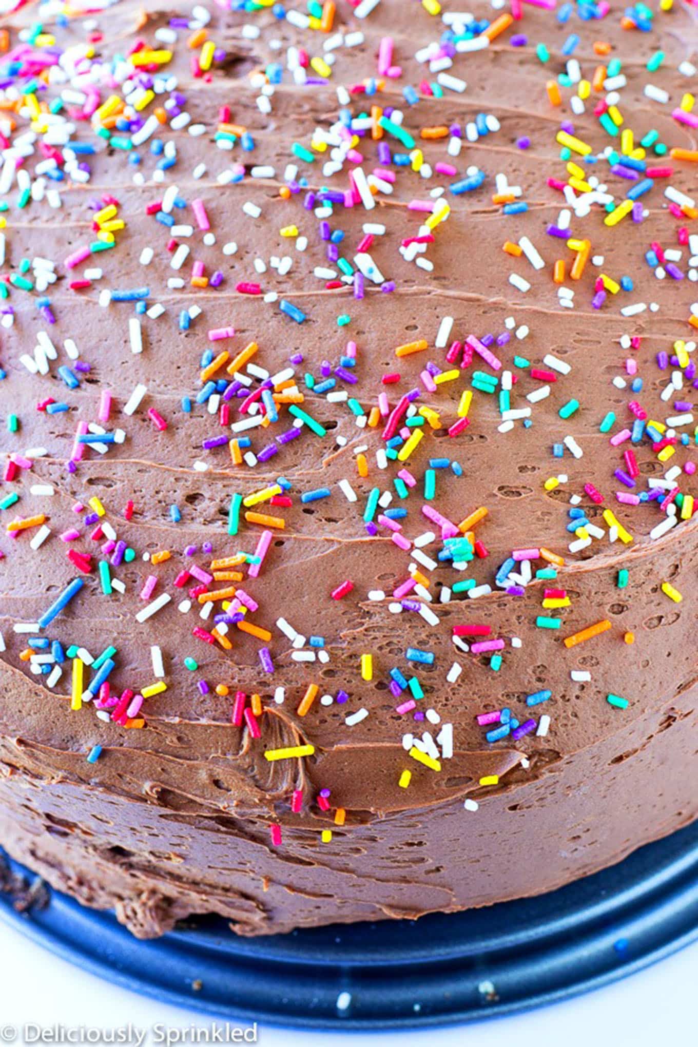 Chocolate frosting spread over a cake with sprinkles added.