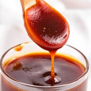 A spoonful of honey BBQ sauce up over the jar with some dripping back in.