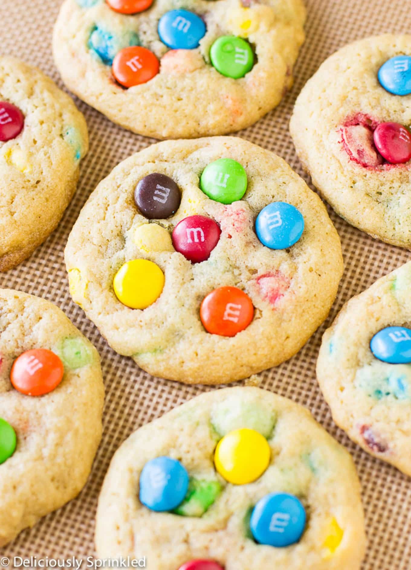 Close up of baked M&M cookies on a baking tray lined with a silpat.