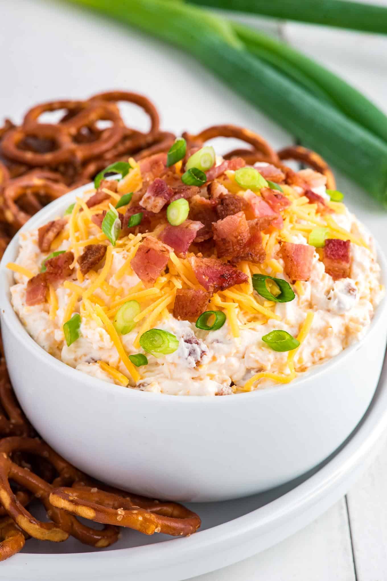 Bacon cheddar ranch dip in a bowl on a platter with pretzels.