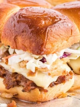 A closeup of a pulled pork slider with coleslaw on the table.