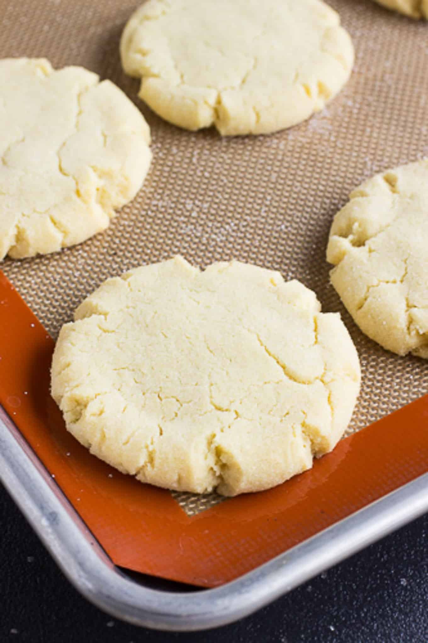 A close up of easy sugar cookies on a baking tray with a silpat. 