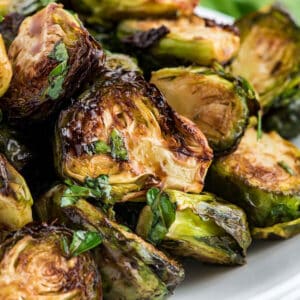 A close up of balsamic glazed air fryer Brussels sprouts in a serving dish.