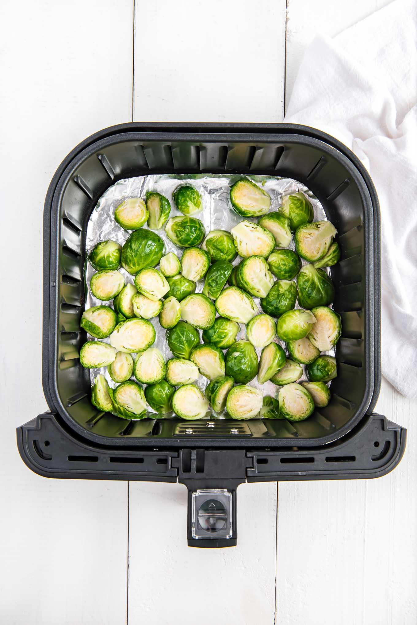 An overhead image of halved Brussels sprouts laid out in the air fryer basket.