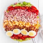 A bowl of Chef salad on the table with all the ingredients laid out in rows.