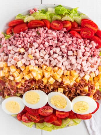 A bowl of Chef salad on the table with all the ingredients laid out in rows.