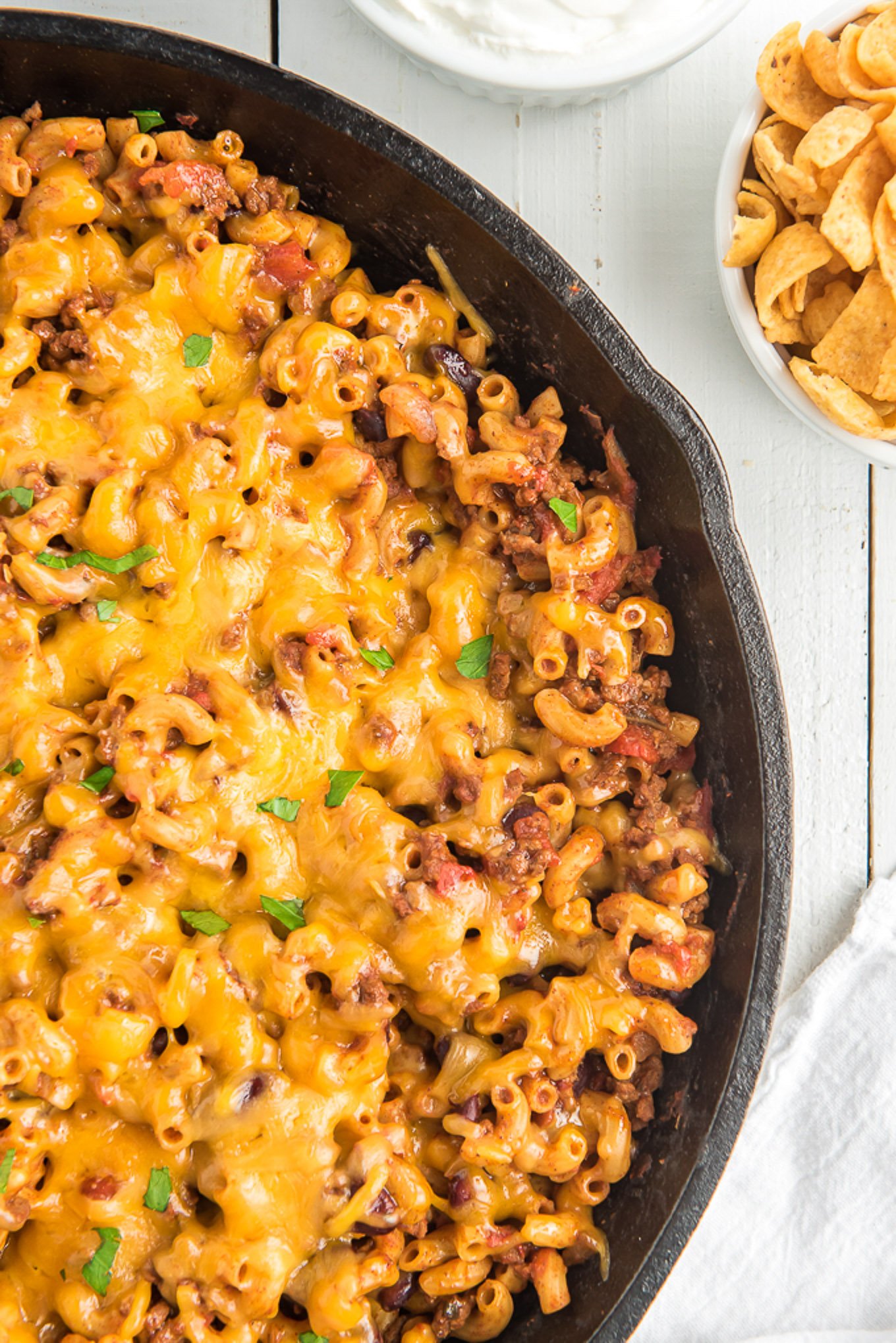 Close up of a half a pan of chili mac in a skillet topped with cheese.