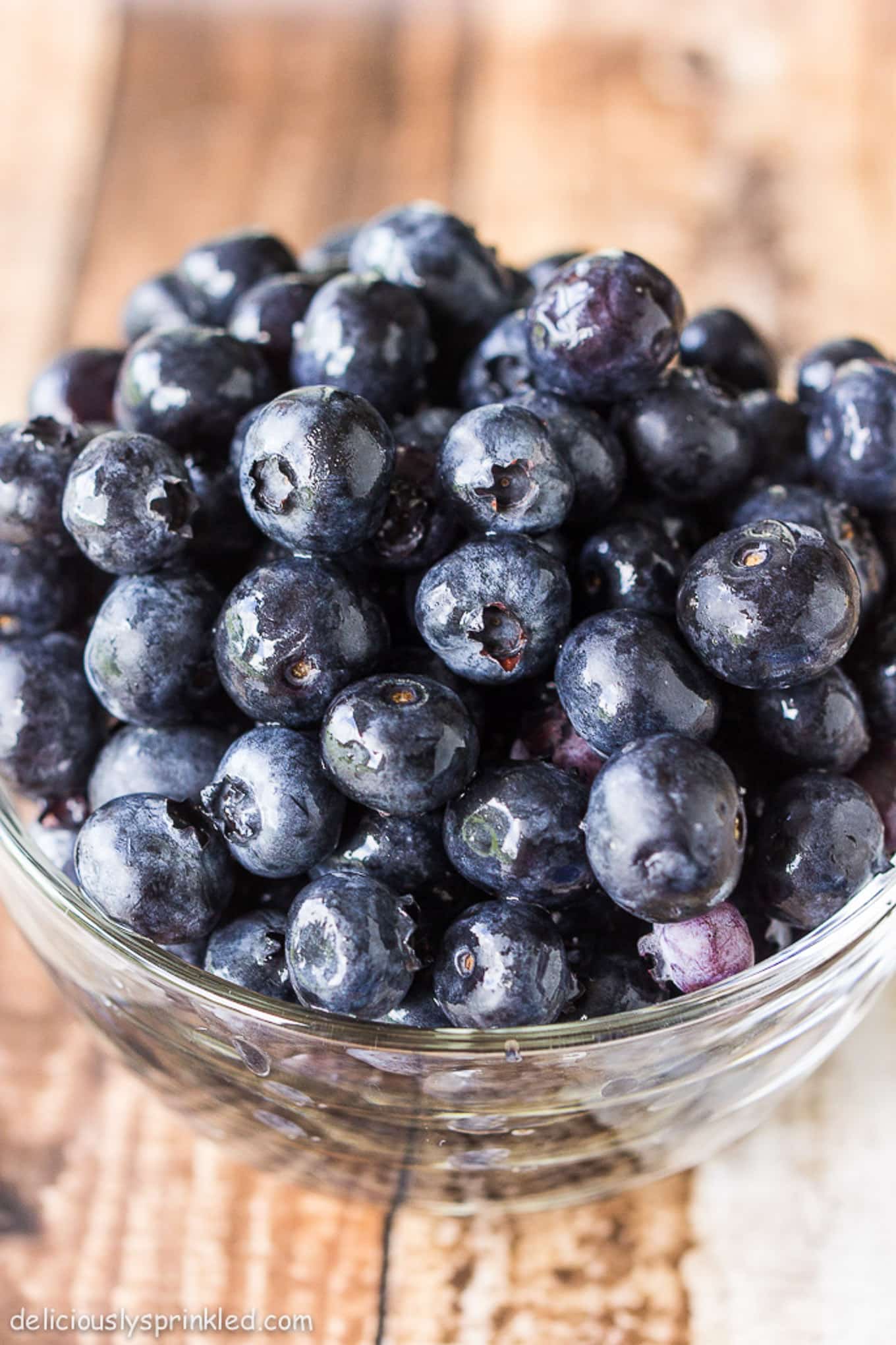 A bowl of fresh blueberries on a wooden table.