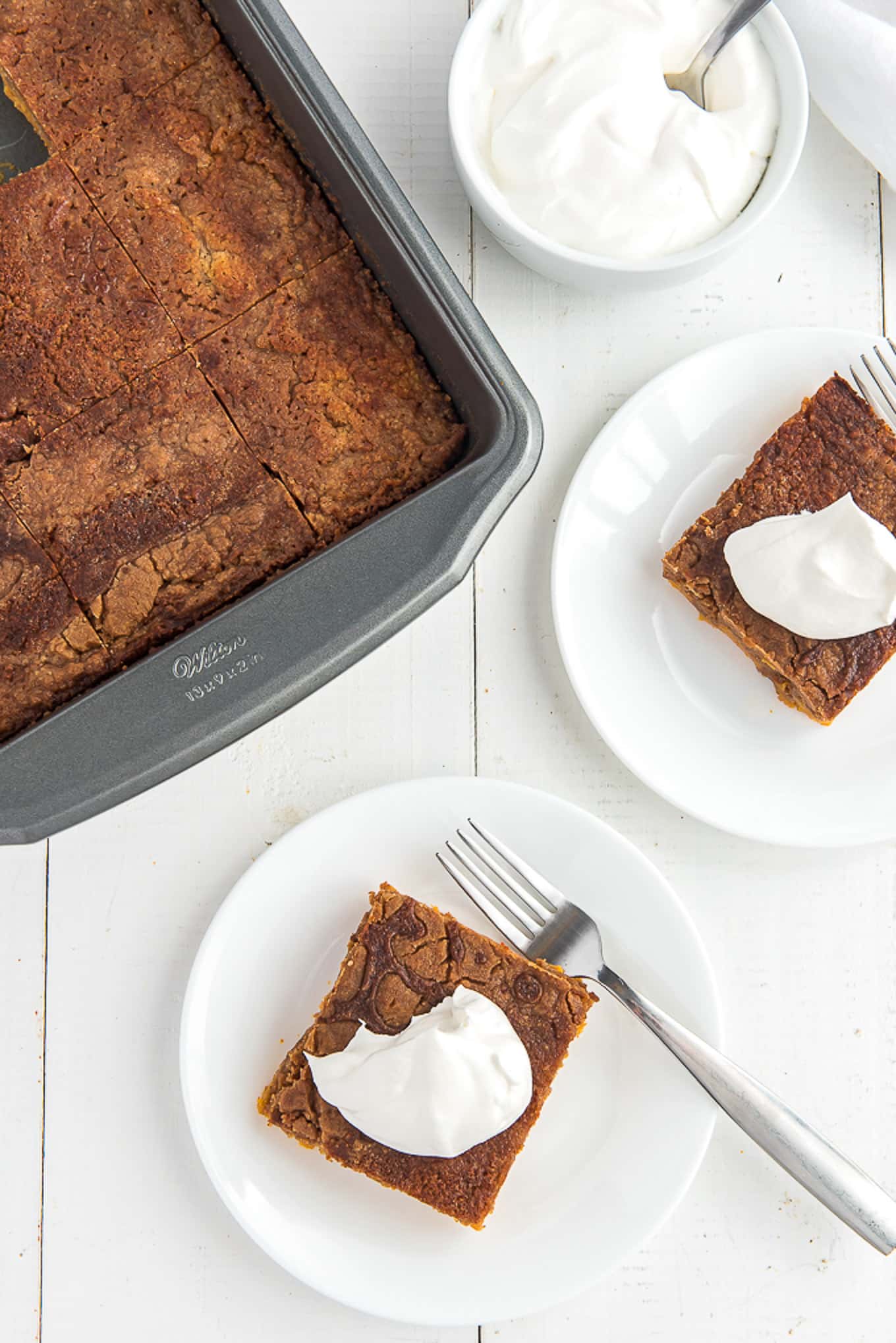 Pan of pumpkin cake cut into squares with pumpkin cake served on a plate. 