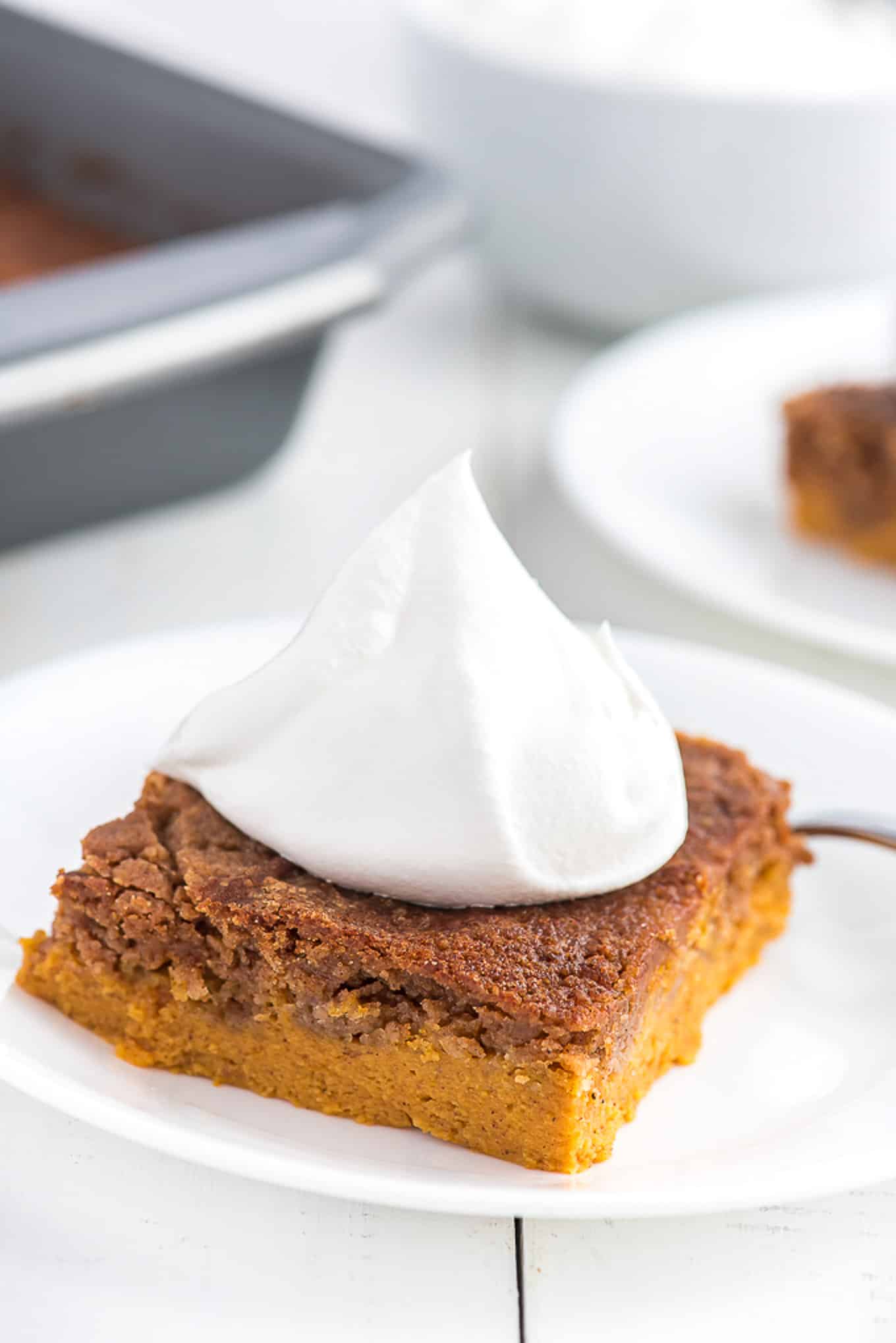 a slice of pumpkin cake topped with cool whip on a plate.