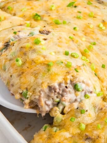 A spoon scooping out a portion of hamburger hash brown casserole to serve.