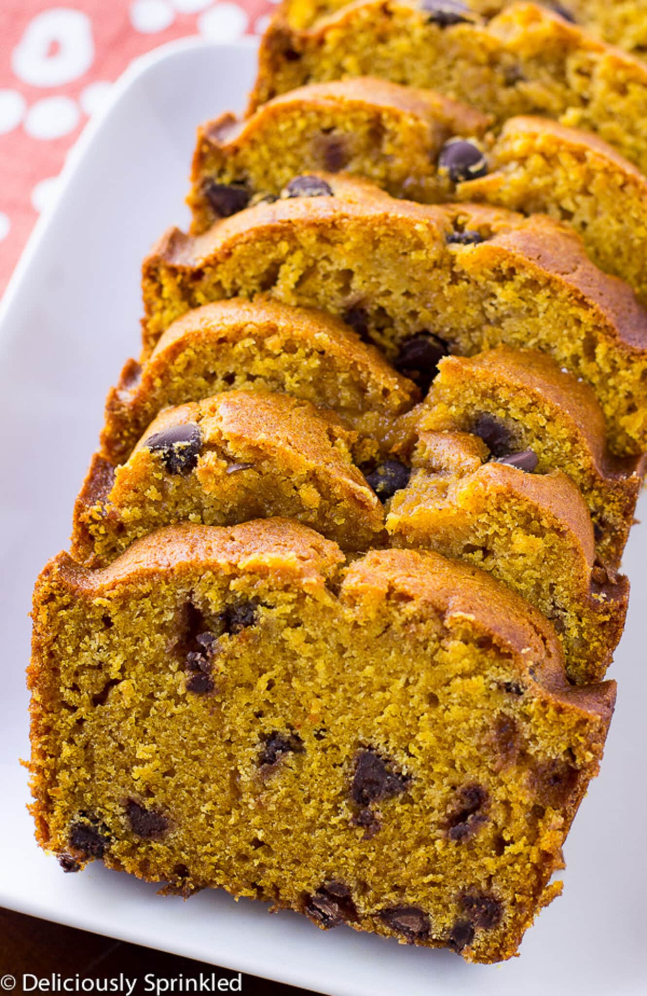 Pumpkin bread with chocolate chips sliced and laid out on a white plate on the table.