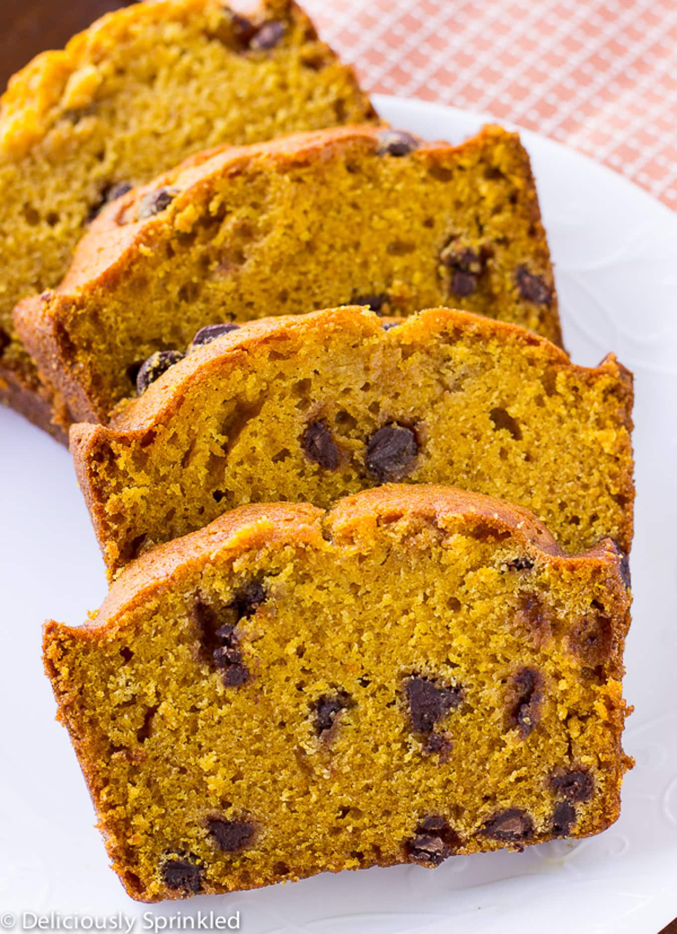 Slices of chocolate chip pumpkin bread fanned out on a white plate.