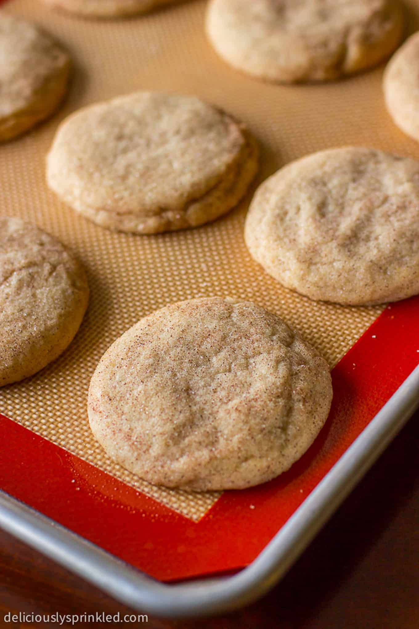 Baked snickerdoodle cookies on a baking sheet with a silpat. 