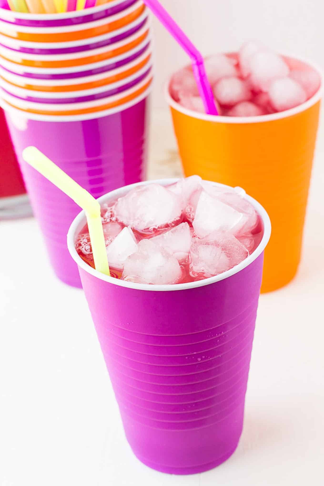 Multi colored solo cups with party punch in them.