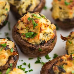 Air fryer stuffed mushrooms on a white plate garnished with parsley.
