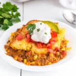 Plated Mexican corn casserole topped with sour cream.