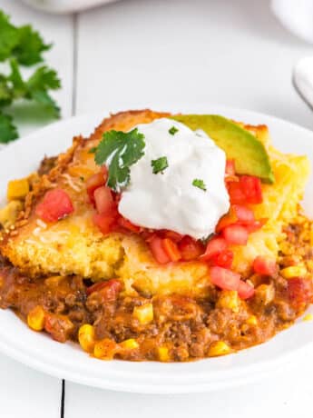 Plated Mexican corn casserole topped with sour cream.