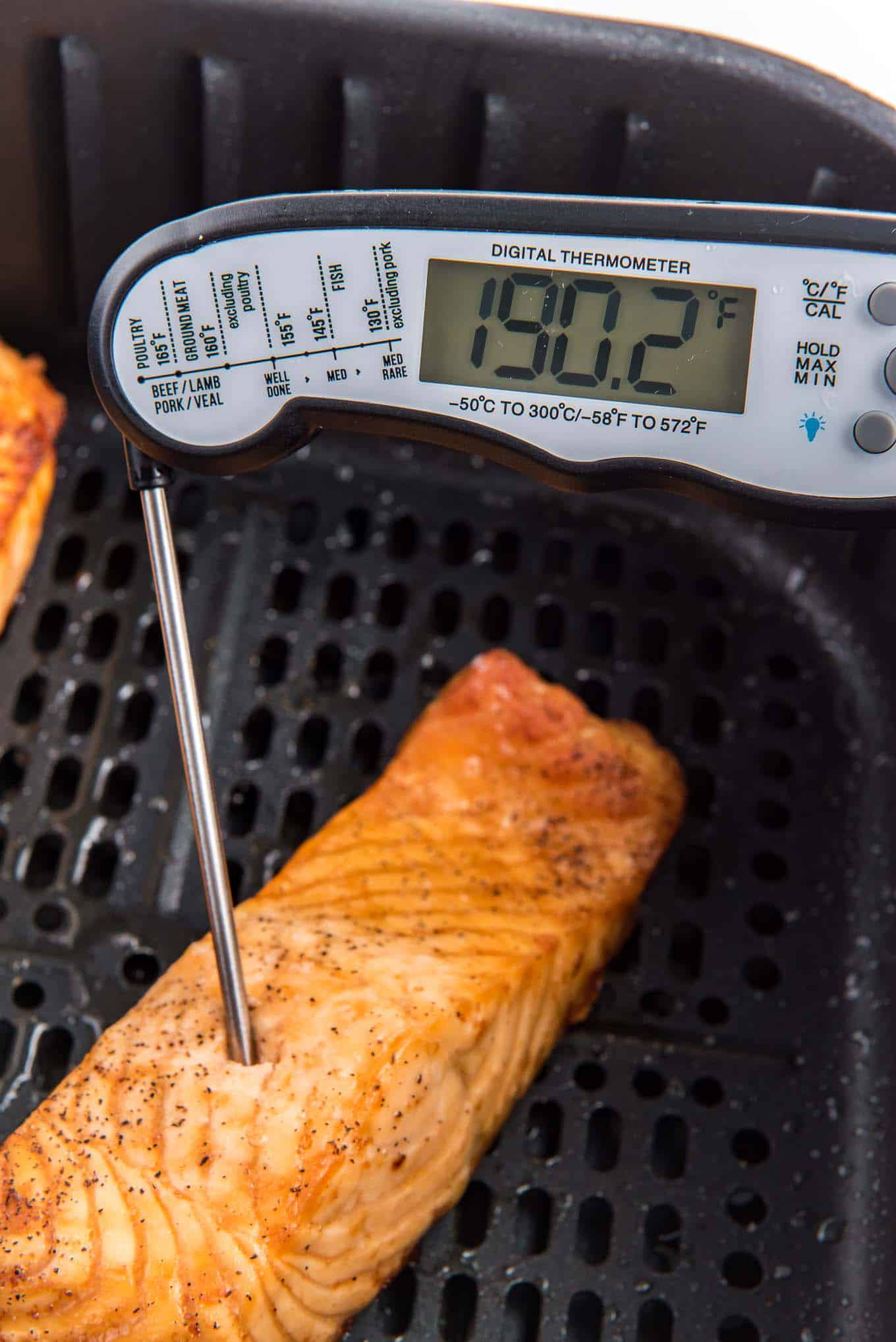 A thermometer inserted into the salmon fillet to take the temperature.